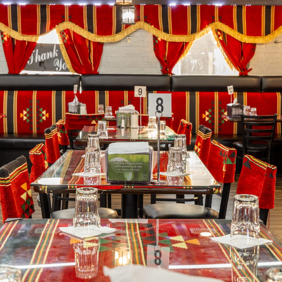 Restaurant interior with red and black patterned seating, glass-topped tables, and traditional decor.