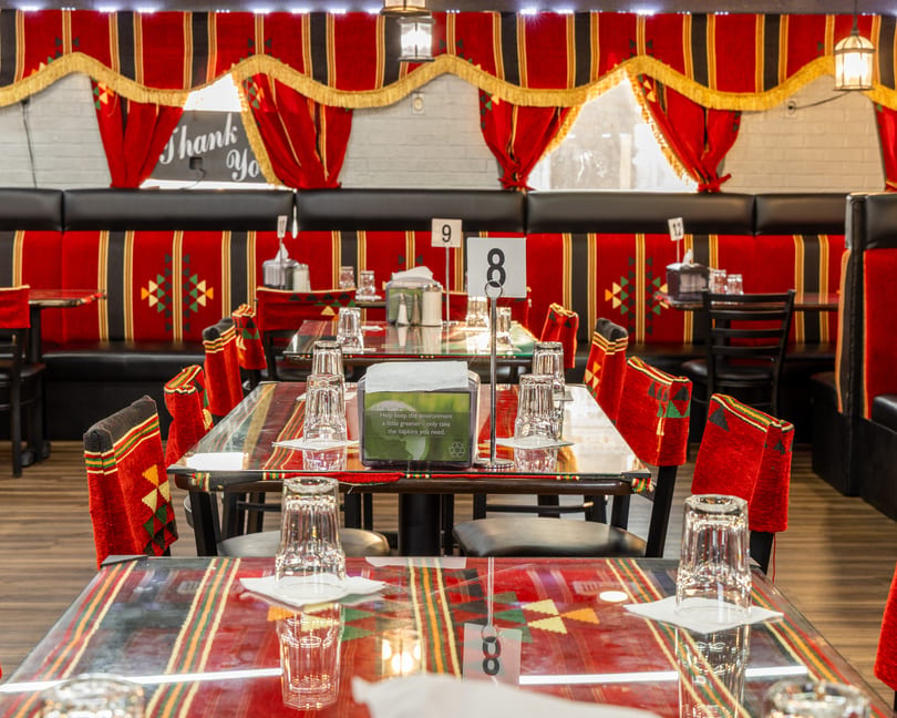 Restaurant interior with red and black patterned seating, glass-topped tables, and traditional decor.