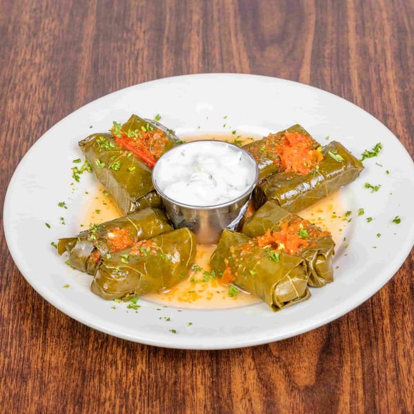 Grape leaves stuffed with rice and herbs, topped with red sauce and served with tzatziki.